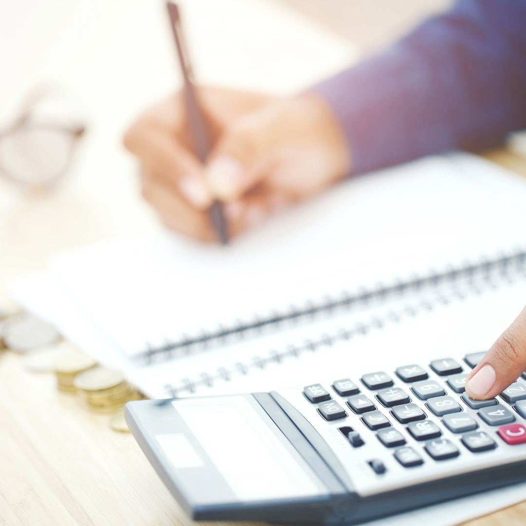 person using calculator while writing notes