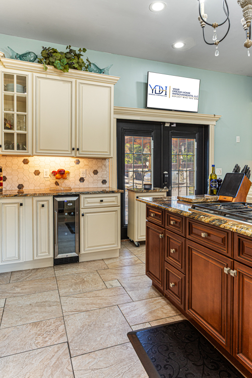 Modern kitchen with cream and wood cabinetry, granite countertops, and a wine cooler.
