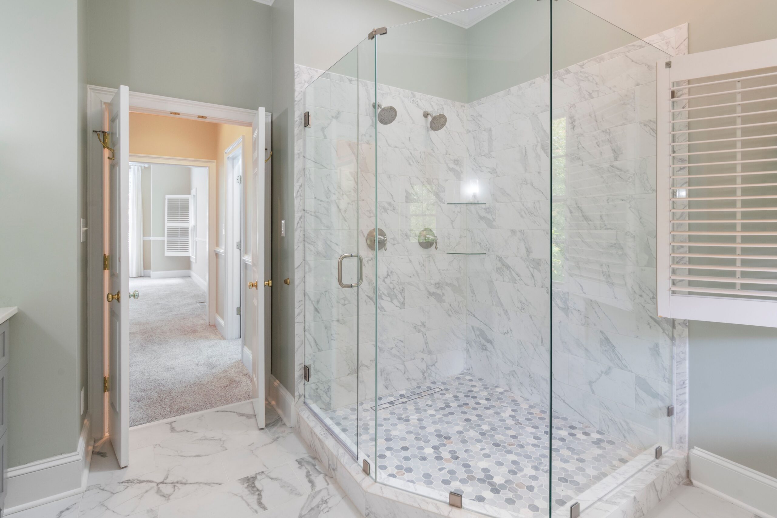 Spacious luxury bathroom featuring a contemporary marble shower with glass doors and elegant interior design.